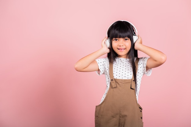 Aziatische kleine jongen van 10 jaar die lacht en naar muziek luistert met een draadloze headset op haar hoofd