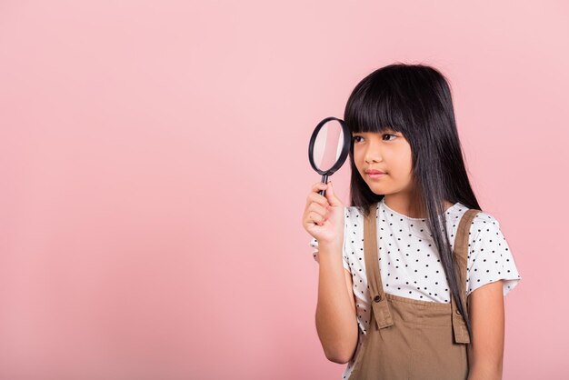 Aziatische kleine jongen van 10 jaar oud grappig kijkend door vergrootglas