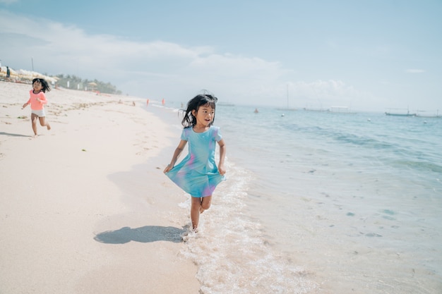 Aziatische kleine meisjes rennen en lachen op het strand