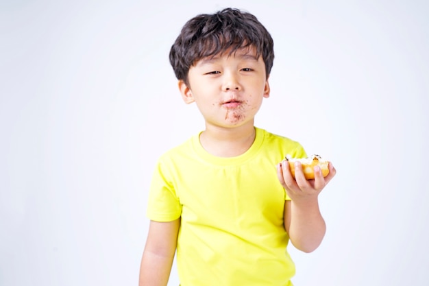 Aziatische kleine schattige jongen eet grote donut geïsoleerd op wit