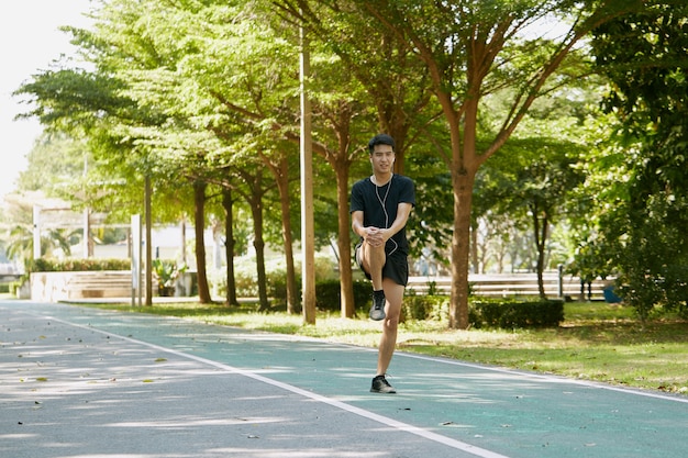 Aziatische knappe mannen warmen zich op voordat ze 's ochtends in het park wandelen en joggen.