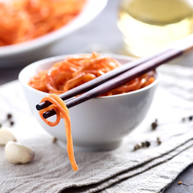 Aziatische Koreaanse wortelsalade met kruiden en knoflook in de houten horizontale kom