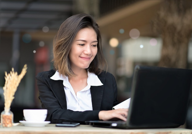 Foto aziatische laptop van het vrouwengebruik voor het werk in koffiewinkel