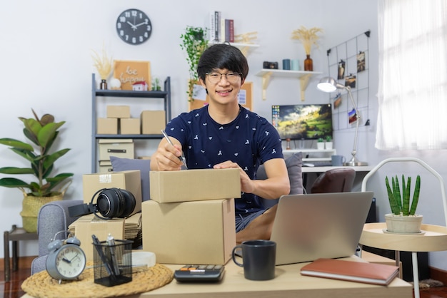 Aziatische man aan het werk verkoopt online schrijfadres op pakket bestellingen