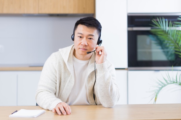 Aziatische man die online praat tijdens een videogesprek in de thuiskamer met headset