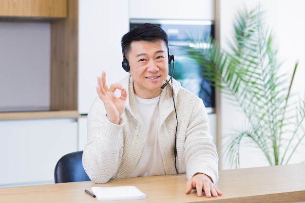 Aziatische man die online praat tijdens een videogesprek in de thuiskamer met headset