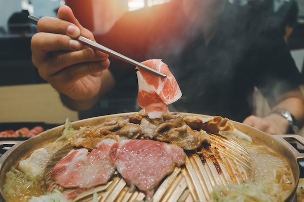 Aziatische man die yakiniku-voedsel eet Japanse versie van Koreaanse BBQ Rauw vlees op een bord en gegrild vlees met saus Wagyu A5 Japans rundvlees dat als het beste rundvlees ter wereld wordt beschouwd