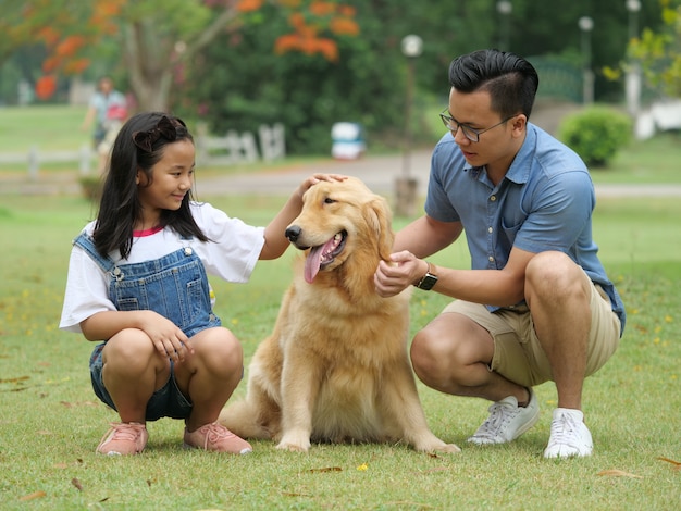 Aziatische man en meisje met hond golden retriever in park