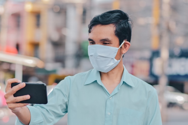 Aziatische man gebruik gezichtsmasker Videogesprekconferentie op straat in stad nieuw normaal sociaal afstandsconcept