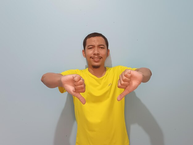 Aziatische man gele t-shirt duimen naar beneden