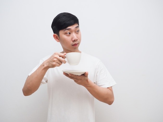 Aziatische man houdt koffiekopje in de hand en kijkt naar de rechterkant met een gelukkige glimlach op wit isolaat