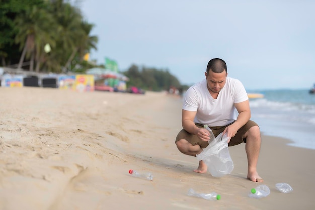 Aziatische man houdt vuilnis in de zee strandmensen vrijwilligers houden vuilnis plastic fles