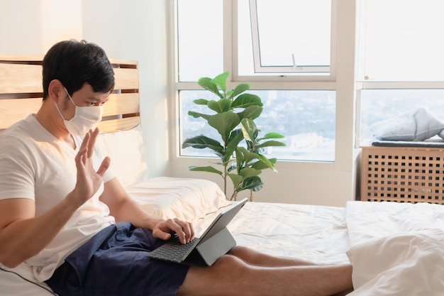 Aziatische man is in een onlinevergadering in concept van werk vanuit huis.