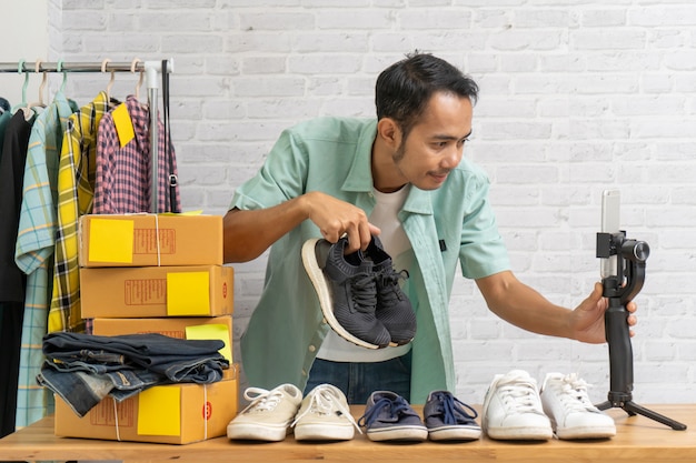 Aziatische man met behulp van slimme mobiele telefoon met live verkoop van schoenen online