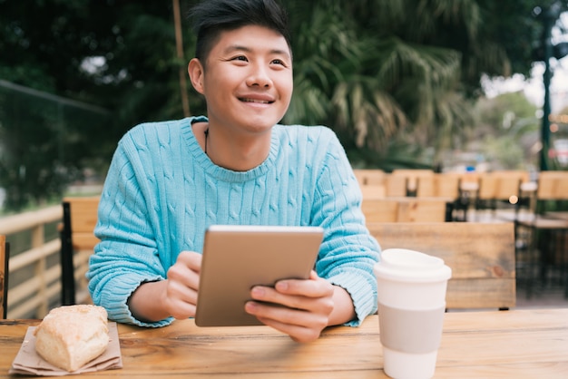 Aziatische man met behulp van zijn digitale tablet