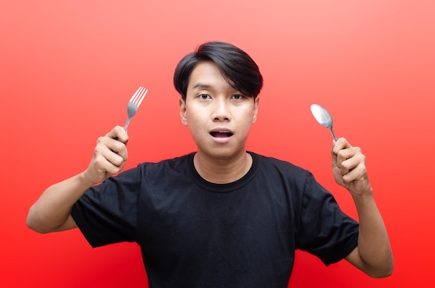 aziatische man met een gelukkige uitdrukking met lepel en vork. Vasten en dieet concept.
