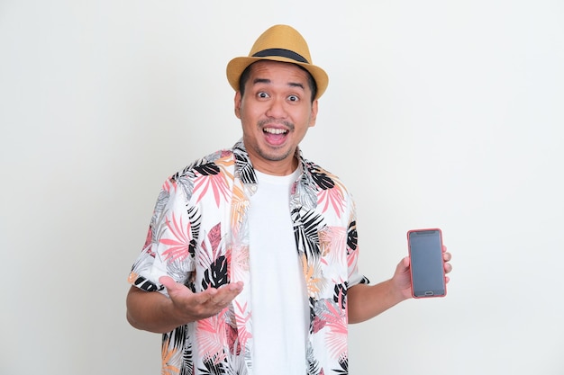 Aziatische man met een strandoverhemd met een leeg gsm-scherm met opgewonden uitdrukking