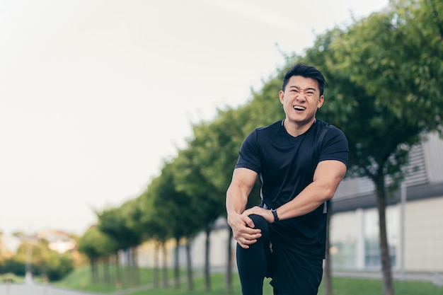 Aziatische man met kniepijn na hardlopen en fitness, ernstige pijn in de benen