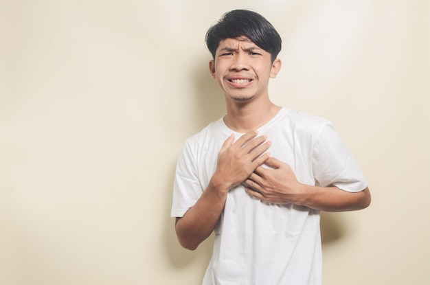 Aziatische man met witte t-shirt pijn op de borst geïsoleerde achtergrond