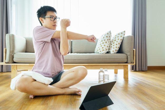 Aziatische man uitoefenen in de woonkamer en op zoek naar digitale tablet