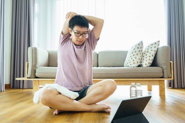 Aziatische man uitoefenen in de woonkamer en op zoek naar digitale tablet