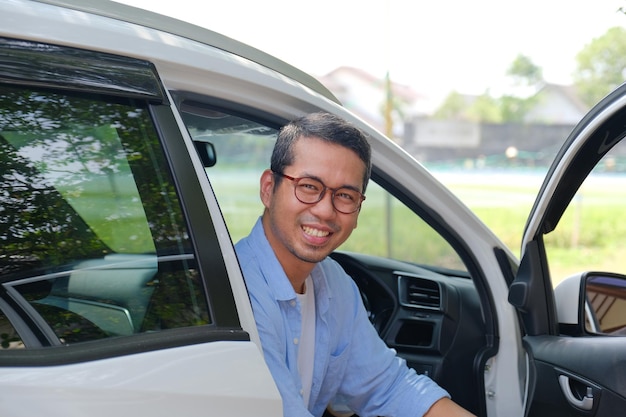 Aziatische man zit in zijn auto en toont een gelukkige uitdrukking