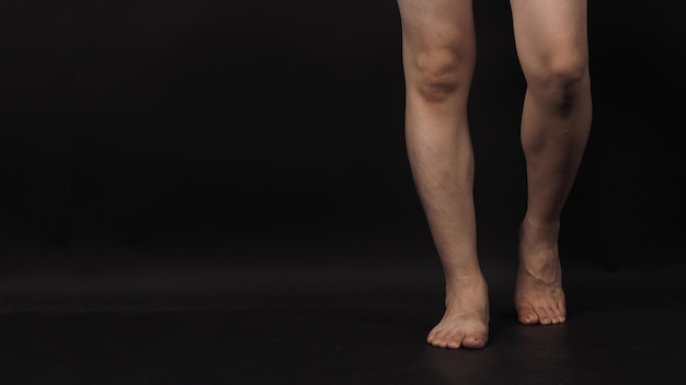 Aziatische mannelijke benen en blootsvoets is geïsoleerd op zwart background.walking concept