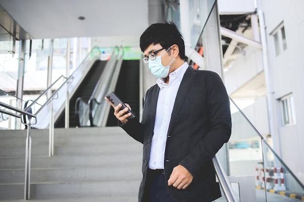 Aziatische mannelijke freelancer met een chirurgisch masker die 's ochtends in de metro gaat werken