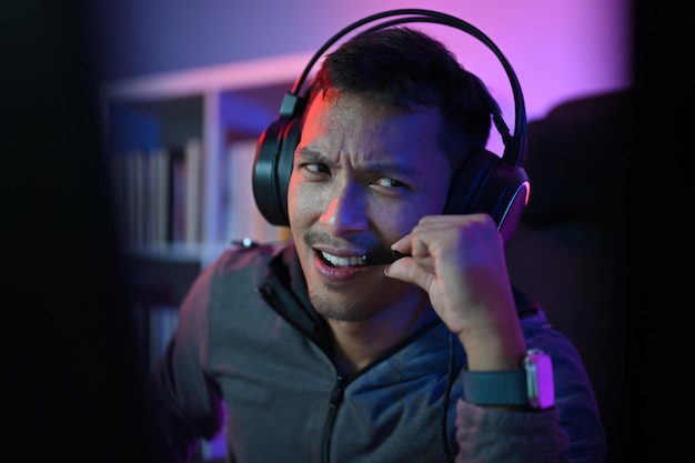 Aziatische mannelijke gamer die online videogames speelt op pc en met spelers praat via chat via microfoons