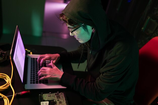 Aziatische mannelijke hacker met behulp van een laptop in de computerserverruimte. cybercriminaliteit en hackingconcept