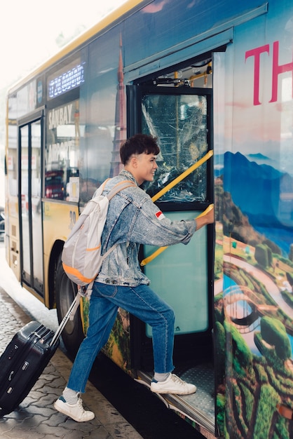 Aziatische mannelijke jonge reiziger die op de toeristenbus stapt om te reizen