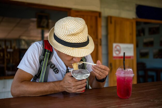 Aziatische mannelijke toeristen zitten en eten heerlijk in stan noodles voor toeristen en easy food concept
