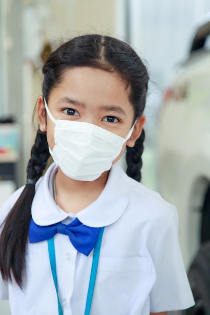 Aziatische meisje in Thaise student uniform dragen virus beschermende griep masker