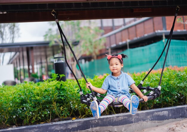 Aziatische meisje, zittend op een schommel in de speeltuin