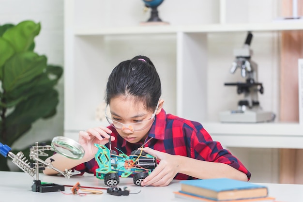 Aziatische meisjes bouwen robotwagens. Kinderen leren robotvoertuigen programmeren.