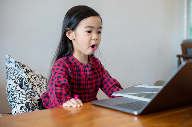 Aziatische meisjes of dochters gebruiken notebooks en technologie om online te leren tijdens schoolvakanties en thuis naar tekenfilms te kijken. Educatieve concepten en activiteiten van het gezin