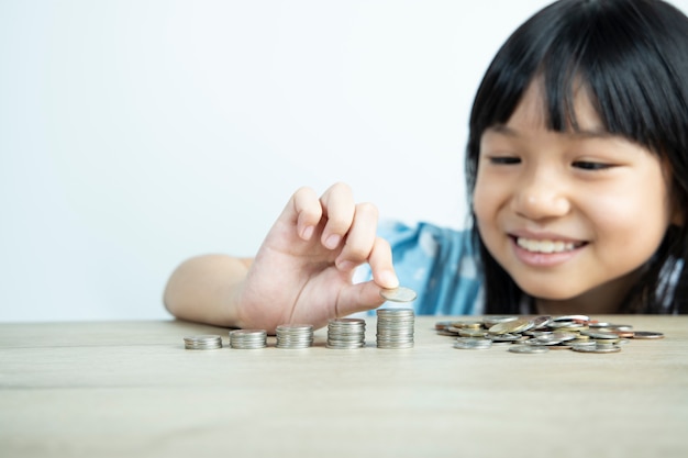 Foto aziatische meisjes regelen graag munten en tellen munten om geld te besparen met de witte muur.