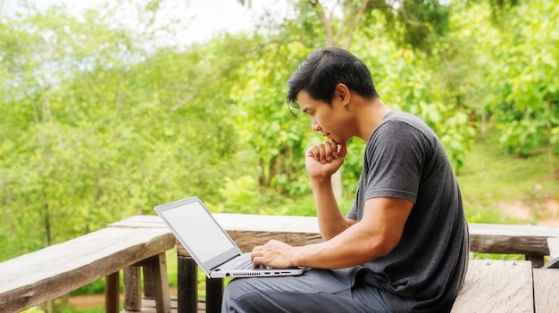 Aziatische mens die laptop op het balkon met behulp van.