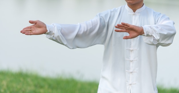 Foto aziatische mens die met tai chi in de ochtend bij het park, chinese vechtsporten, gezonde zorg voor het levensconcept uitwerken.