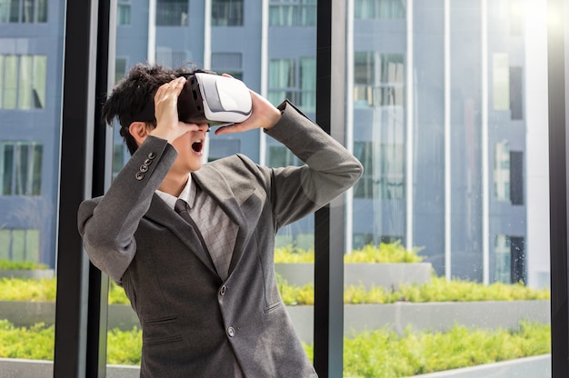 Aziatische mens die virtuele werkelijkheid met pak draagt ​​bij de moderne bouw, VR-technologieconcept