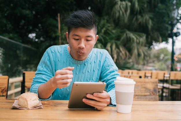 Aziatische mens die zijn digitale tablet gebruikt.