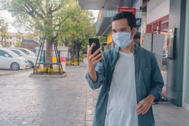 Aziatische mens een dragend gezichtsmasker die de levensstijl nieuwe normale sociale afstand houden van de celtelefoon