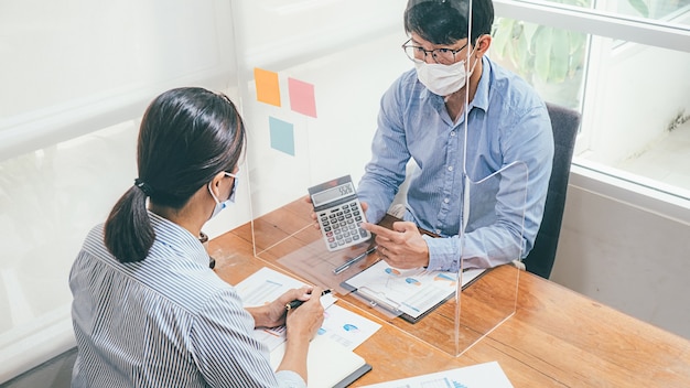 Aziatische mensen Succesvolle Teamwork Business dragen van een medisch masker en werken. Werk vanuit een privékantoor Sociale afstand in de situatie van een uitbraak van het coronavirus