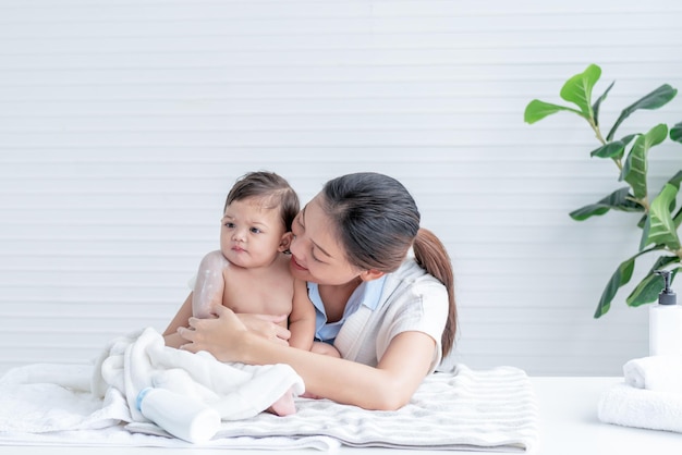 Foto aziatische moeder aantrekkelijk en jong is het toepassen van talkpoeder aan haar 7 maanden oude dochter na het baden om te helpen verminderen van de uitslag naar aziatische familie en baby baby concept