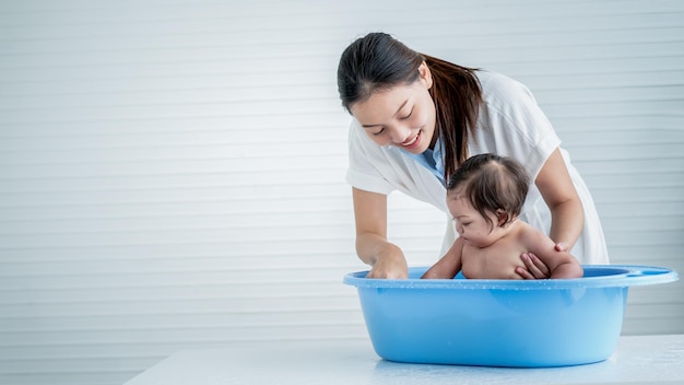 Aziatische moeder baden haar 7 maanden oude dochter die de baby glimlachend en gelukkig met witte achtergrond aan Aziatische familie en baby douche concept