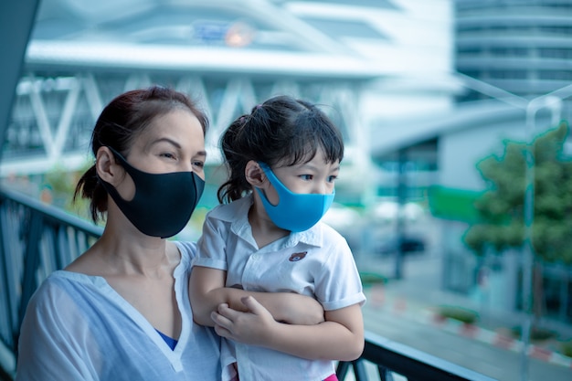 Aziatische moeder en dochter met medisch masker op de stadsstraat.