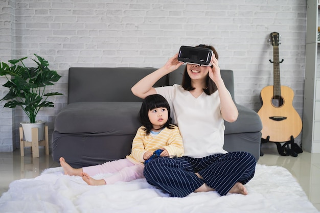 Aziatische moeder en dochter spelen VR-game om samen thuis te entertainen, familie vrolijk samen in huis op vakantie. Gelukkig familie metaverse VR-technologieconcept.