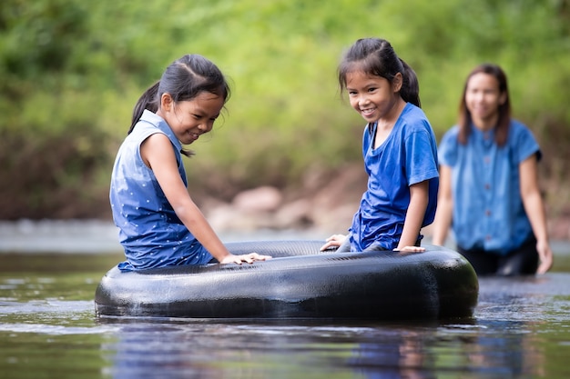 Aziatische moeder en haar dochters die samen in de rivier spelen