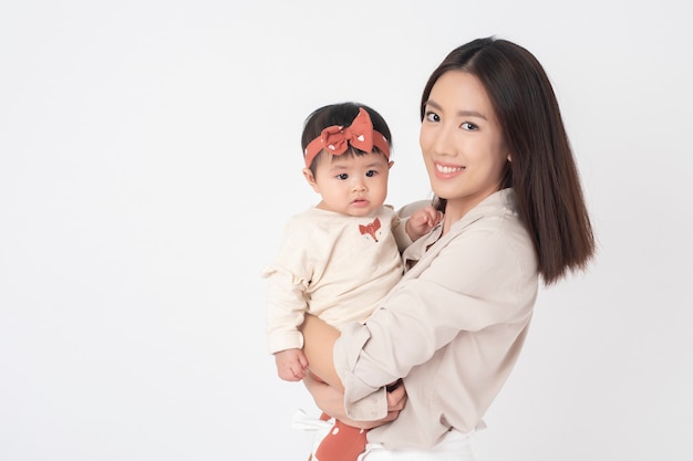 Aziatische moeder en schattig babymeisje zijn gelukkig op witte muur