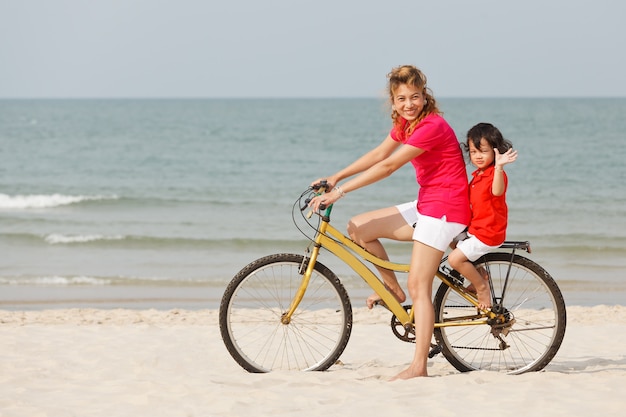 Aziatische moeder en zoon fietsten op tropisch strand tropical